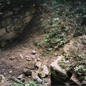 Obr. 62: Veveří - hrad 2002. Průzkum a dokumentace reliktů zdiva mezi věžemi hranolovou a prachovou. Od 80. let minulého stol. zůstaly odkryty relikty kamenného středověkého zdiva s průchodem (bránou ?) na vnější straně současné JV obvodové hradby. Jejich zbytky byly začištěny, zdokumentovány a přesně zaměřeny (foto P. Vitula).