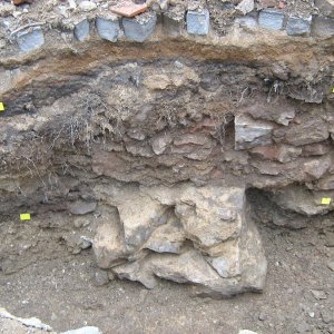 Obr. 149: Veveří – hrad 2017/01. Kanalizace. Profil výkopu s černošedou raně středověkou vrstvou (1. pol. 13. stol.) a reliktem kamenné středověké zídky – pohled od SV (foto P. Vitula).
