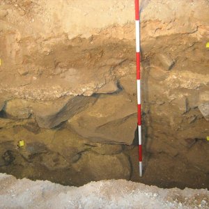 Obr. 162: Veveří – hrad 2017/01. Kanalizace. Profil výkopu s reliktem středověkého kamenného zdiva a maltovou novověkou stavební vrstvou po začištění v průjezdu hlavního paláce – pohled od S (foto P. Vitula).