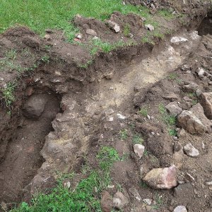 Obr. 191: Veveří – hrad 2021. Páteřní rozvody elektřiny. Výkop pro elektroinstalaci se začištěným reliktem koruny kamenné středověké zdi na nádvoří opyše – celkový pohled od JV (foto P. Vitula).