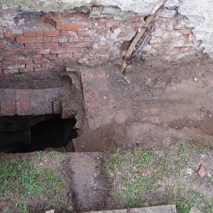 Obr. 246: Veveří – hrad 2023. Severovýchodní průčelí jižní brány – zjišťovací sondáž č. 3. Situace v sondě č. 1 – výkopem byla odkryta další část cihelného kanálu zachycená již v roce 2022 sondou č. 4. Jeho ústí za obvodovou zdí brány padalo svisle podél tarasní zdi do hloubky více než 3 m a nebylo dokopáno. Další část kanálu se stočila podél obvodové zdi brány a pokračovala přes cestu k sondě č. 2  - pohled od SV (foto P. Vitula).